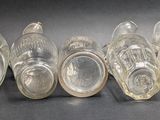 six clear glass bottles lined up in a row on a black surface