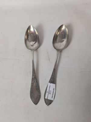 two silver spoons sitting on top of a table next to each other