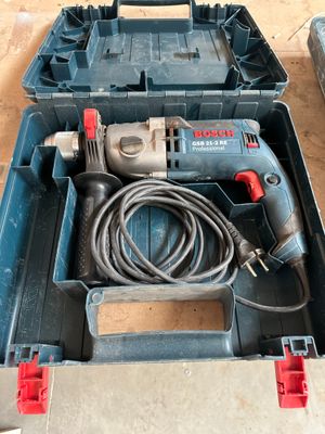une perceuse filaire dans une boîte à outils posée par terre