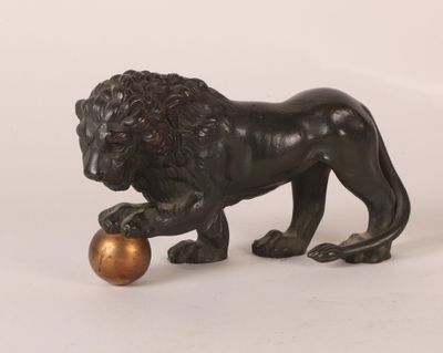 statue en bronze représentant un lion tenant une boule dorée entre ses pattes