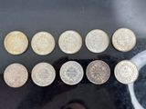 six different british coins sitting on top of a table next to a person ' s hand