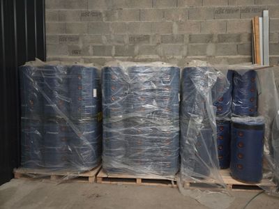 de nombreux rouleaux de plastique bleu sur une palette dans un entrepôt