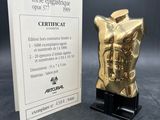 a gold figurine of a torso on a black stand
