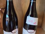 two bottles of wine sitting on a shelf next to each other
