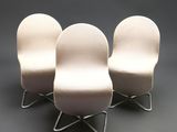 three white chairs sitting on top of each other on a gray surface