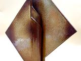 une sculpture métallique représentant un objet de forme carrée posée sur une surface blanche