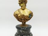 a gold busturine of a woman on a marble base