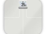 a white bathroom scale with a clock on top of it