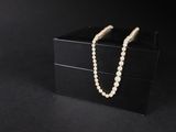 une boîte noire ornée d'un collier de perles, sur fond noir