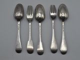 four silver spoons and a fork are lined up on a table