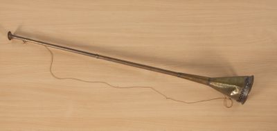 une trompette en laiton posée sur une table en bois et attachée par une ficelle