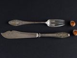 two forks and a knife with nuts on a black surface