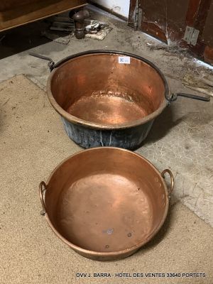 two copper pans sitting on the floor next to each other