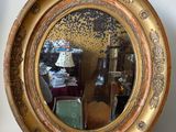 a round mirror hanging on the wall above a table