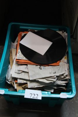 a plastic container filled with newspapers and a black record