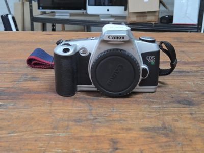 a camera sitting on a wooden table with a camera strap