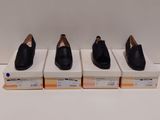trois paires de chaussures noires posées sur des cartons, sur une surface blanche