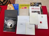 de nombreux livres posés sur une table rouge, avec une horloge en arrière-plan