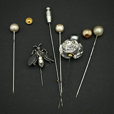 trois broches ornées de perles et d'une abeille sur fond noir