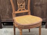 a wooden chair with a wicker seat in front of a wooden fence