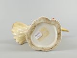 an antique porcelain figurine of a bird with a flower on its head