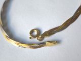 an image of a gold bracelet with a clasp on a white surface