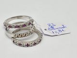three silver rings with pink stones and a tag on a white surface