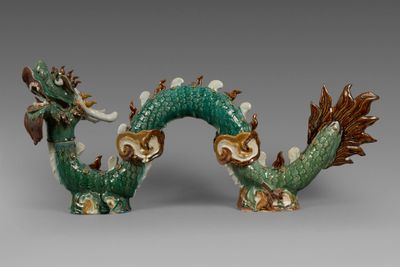 une paire de figurines de dragons verts et marron posées sur une surface grise
