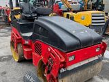 a red and black road roller sitting on top of a parking lot