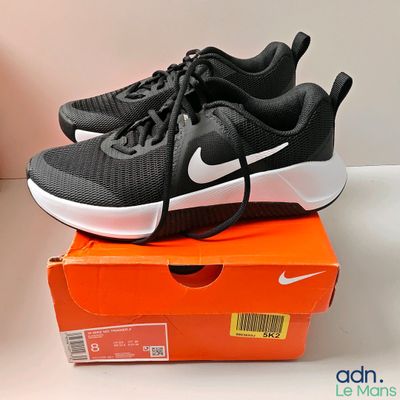des chaussures de course Nike noires et blanches posées sur une boîte orange
