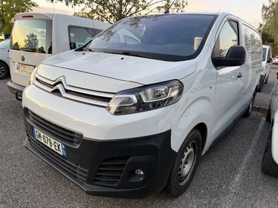 une camionnette blanche garée dans un parking à côté d'autres voitures