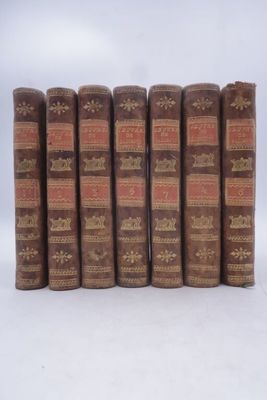 six vieux livres sont alignés sur une surface blanche