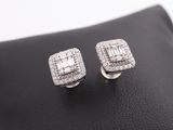 a pair of white gold and diamond earrings on a black leather surface