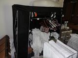 une armoire pleine de vêtements et un lit recouvert d'un couvre-lit noir