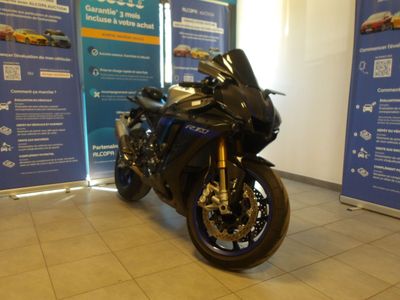 une moto noire garée devant une banderole bleue et blanche