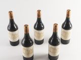 six bottles of wine are lined up in a row on a white surface