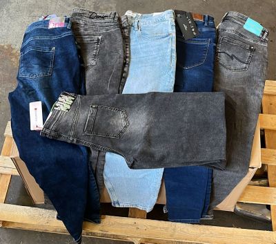 Plusieurs paires de jeans sont empilées sur une palette dans un entrepôt