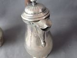 a silver coffee pot with a lid and a spoon next to it