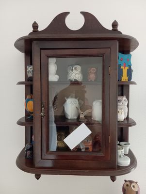 une étagère en bois avec une porte vitrée et une horloge posée dessus
