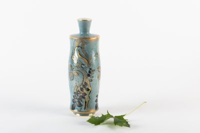 un petit vase bleu avec une feuille par terre