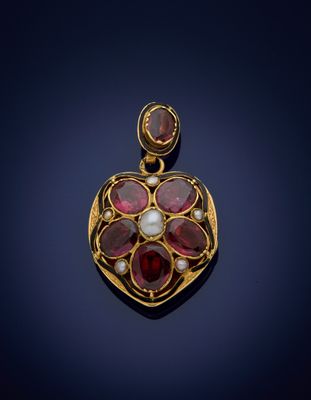 a close up of a gold pendant with red stones and pearls