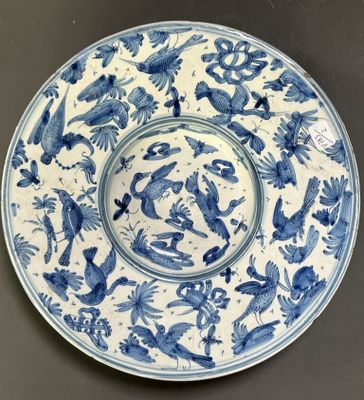 une assiette bleue et blanche décorée d'oiseaux et de fleurs, posée sur une table