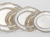 ensemble de quatre assiettes en métal argenté, avec des bords perlés sur fond blanc