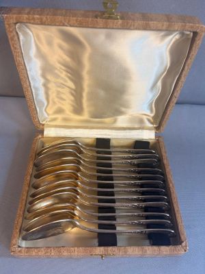 des couverts dans un coffret en bois posé sur une table avec un fond bleu