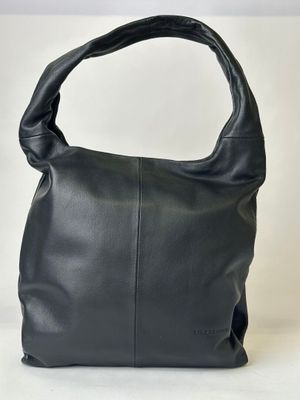 the large black leather bag is sitting on a white surface