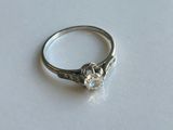 une bague sertie d'un diamant, posée sur une surface blanche