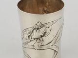 a silver cup with a bird on it and a flower on the side