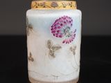 un vase blanc orné de fleurs violettes, posé sur une table