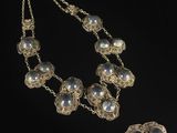 a silver necklace and earrings with pearls on a black background