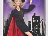 La poupée Barbie porte un costume de sorcière et une cape rouge.
